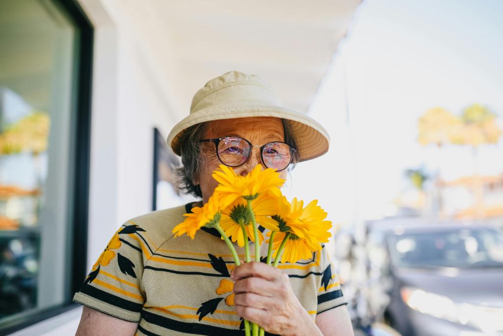 photo of older woman smelling daisys